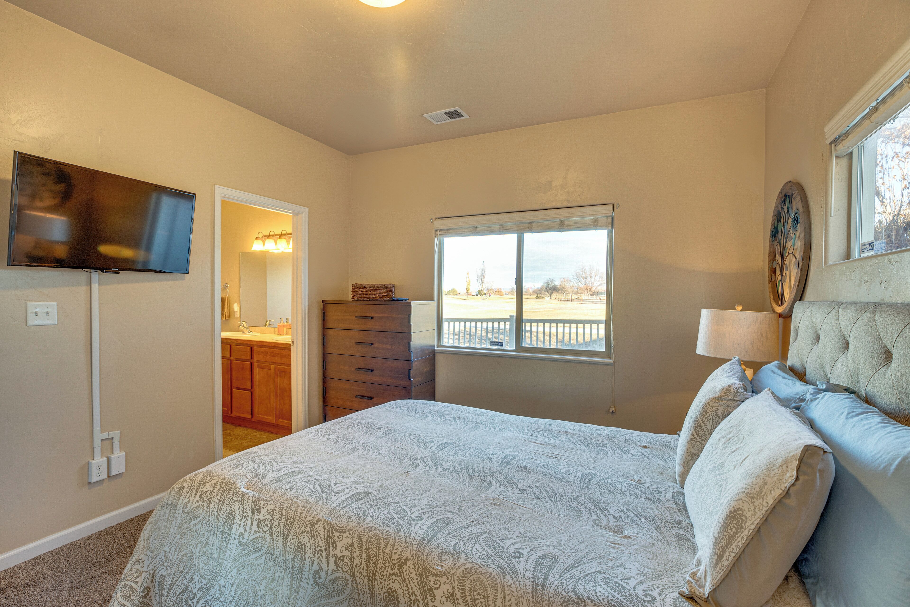 A bedroom with a bed, a dresser, a television, and a window with a view.