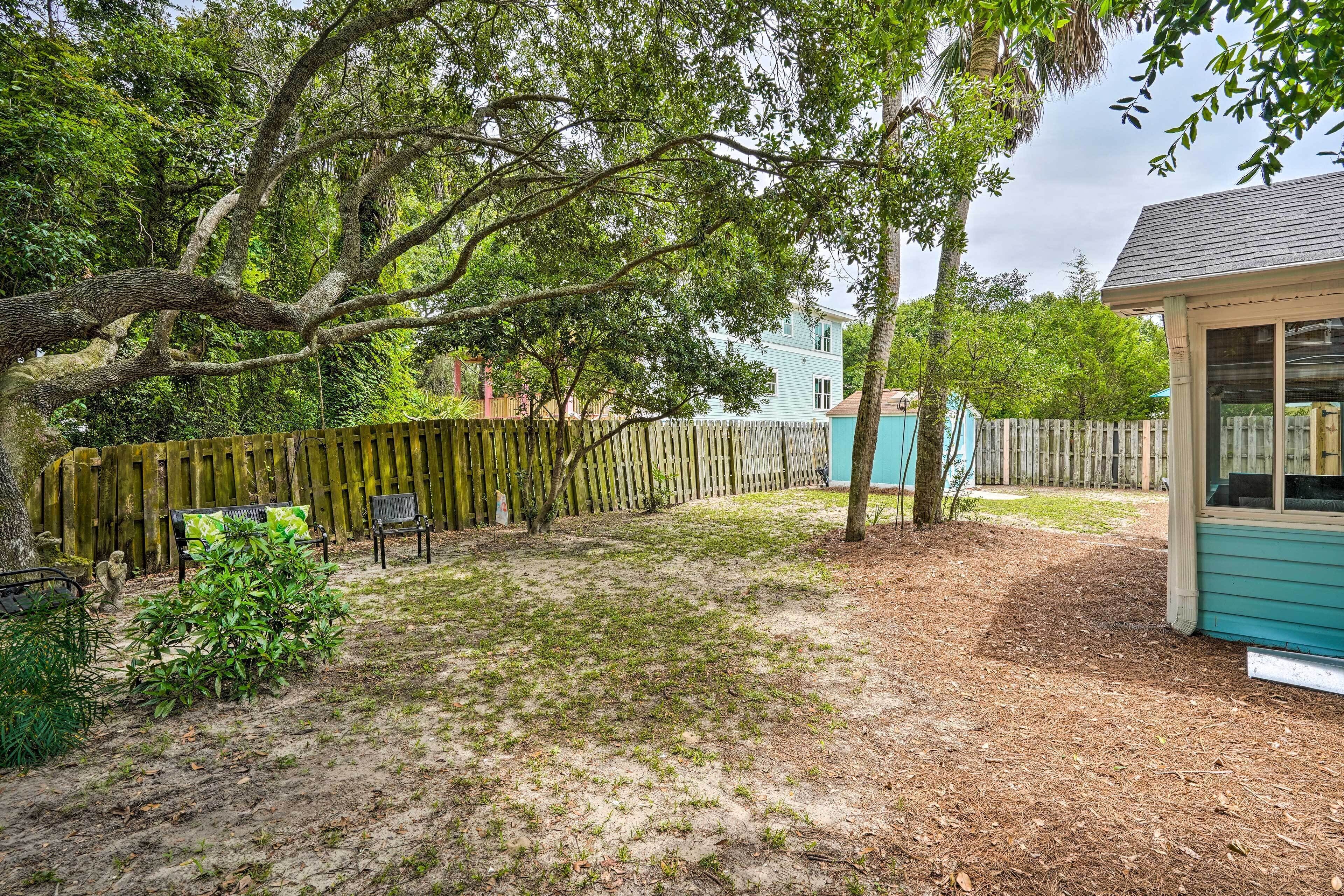 A backyard with a wooden fence, a small shed, and a house in the background.