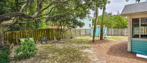 A backyard with a wooden fence, a small shed, and a house in the background.
