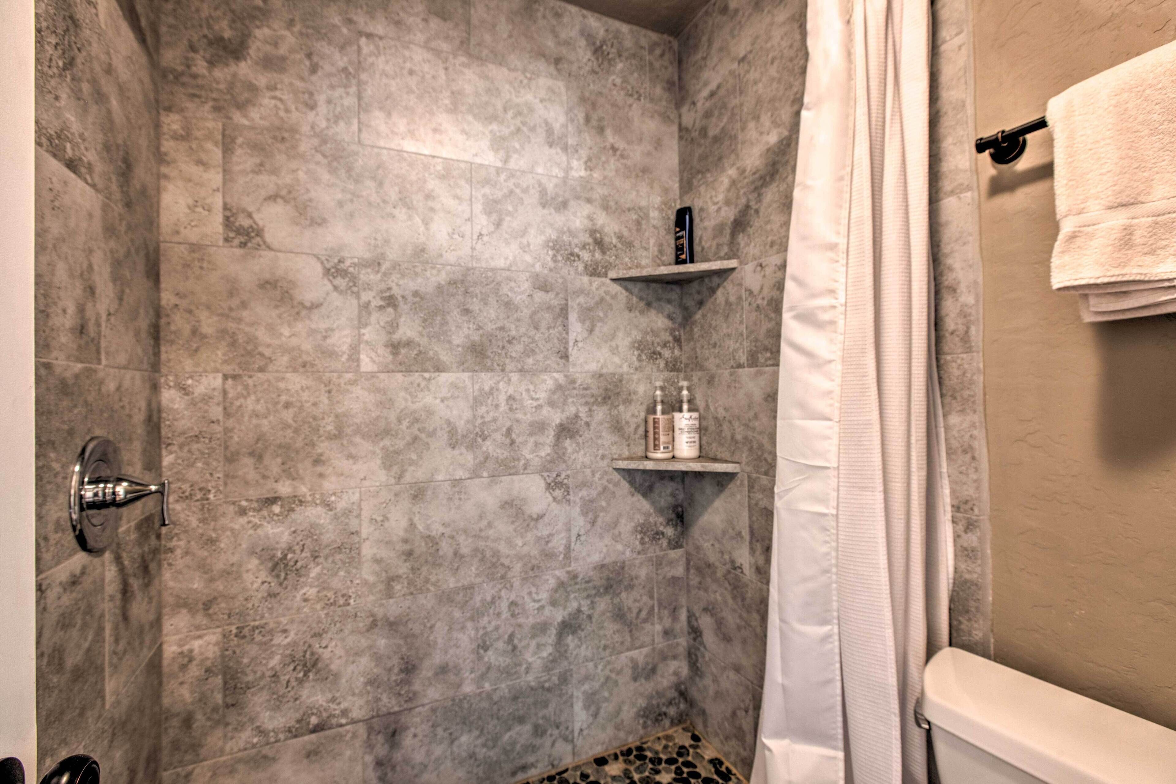 A bathroom with a shower area, a toilet, and a towel rack.