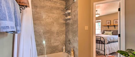 A bathroom with a bathtub, shower, and towel rack.