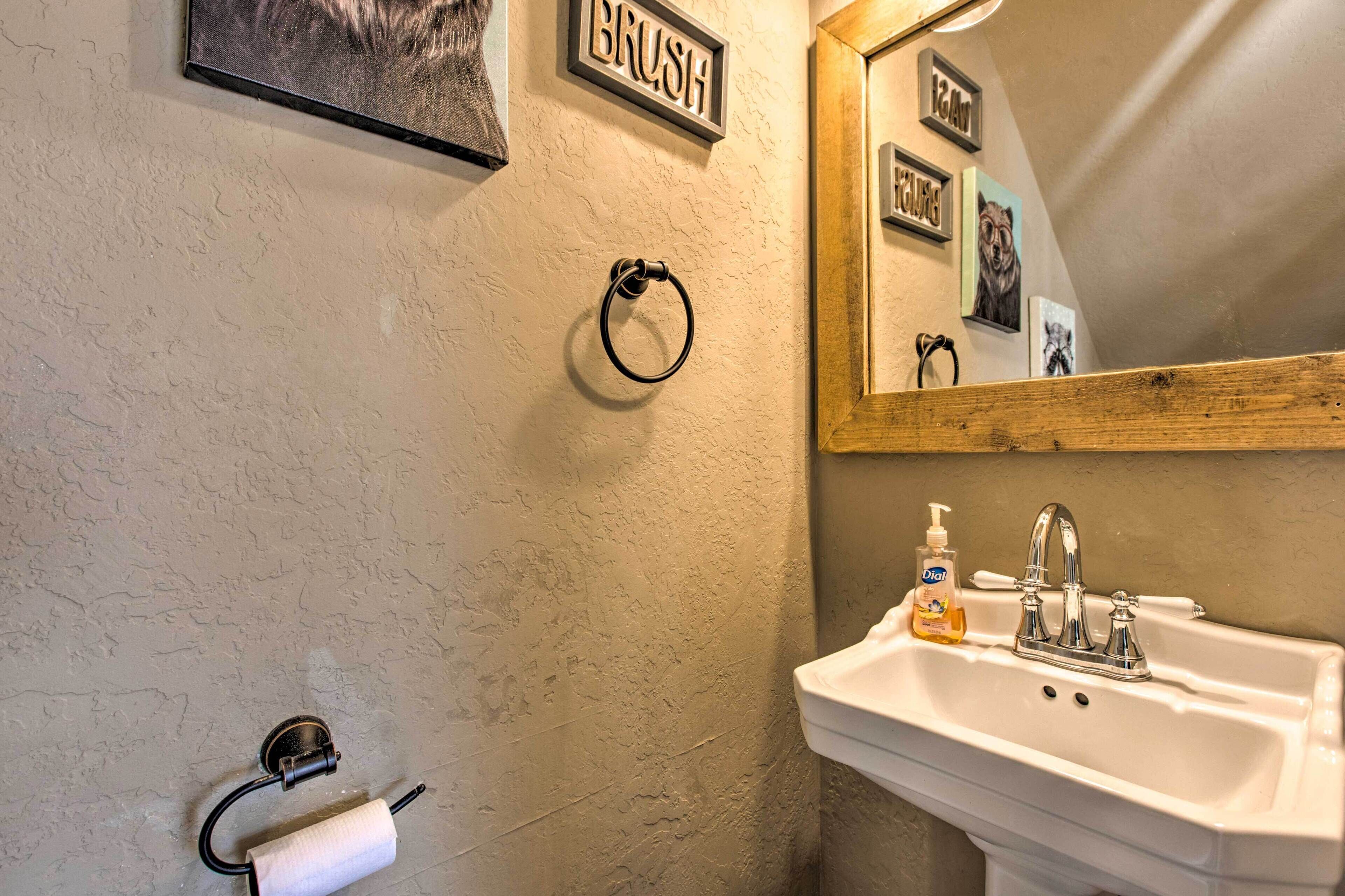 Ein Badezimmer mit Waschbecken, Toilettenpapierhalter, Handseifenspender und einem Spiegel mit Holzrahmen.