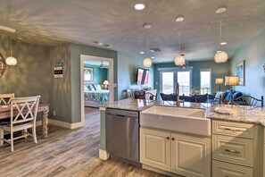 A kitchen with a dishwasher, granite countertops, and a dining area with a wooden table and chairs. - Grand Caribbean - Condo w/ Ocean Views! (Port Aransas)