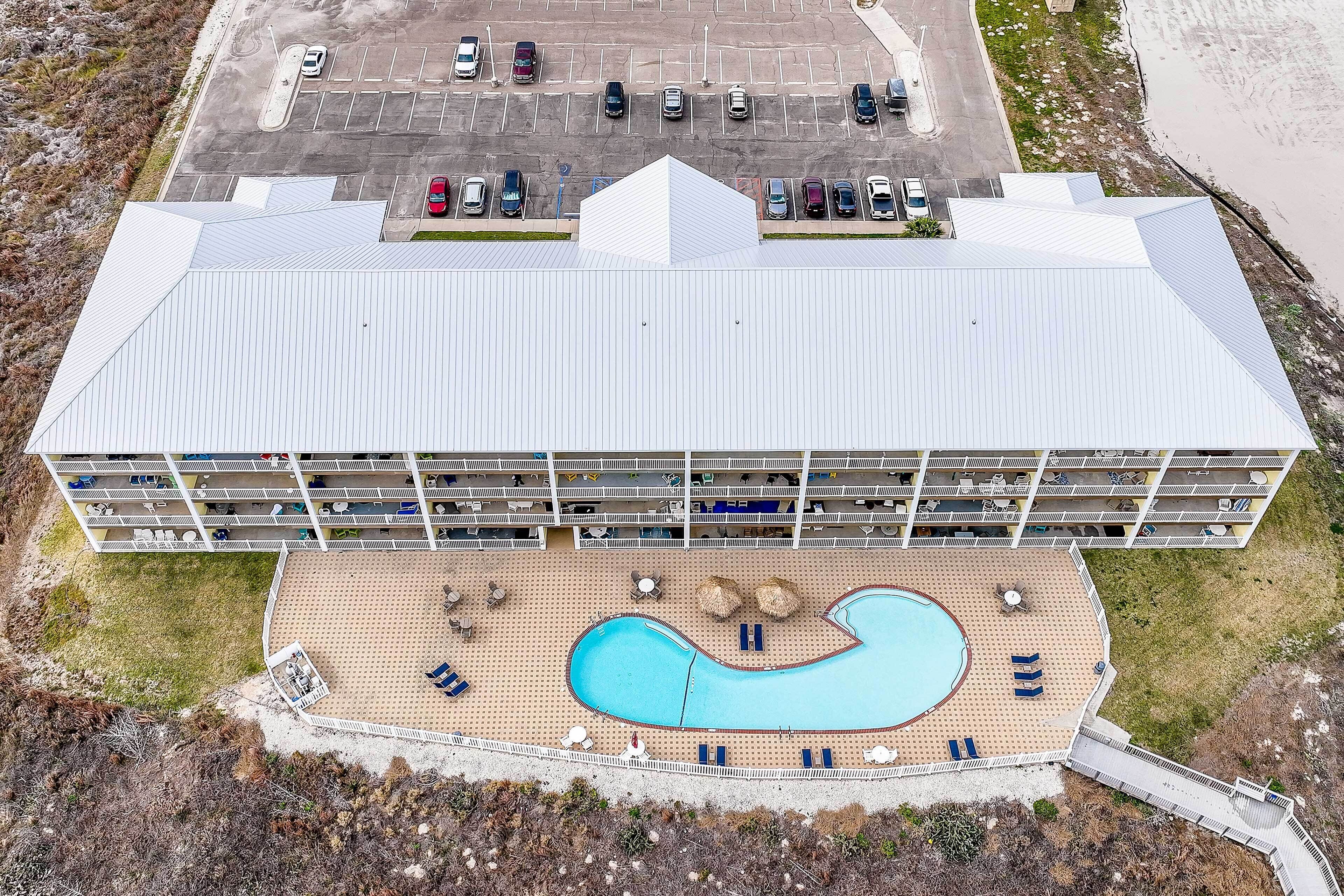 Un hotel con una piscina grande, diversi balconi e un parcheggio.