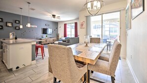 A modern kitchen with a central island, a dining area with a wooden table and chairs, and a living room with a sofa and a TV. - Davenport Retreat w/ Themed Rooms, Patio & Pool! (Davenport)