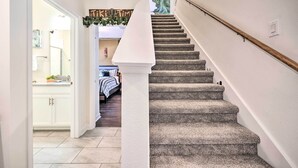 A staircase with a white balustrade and a handrail, leading to a bedroom with a bed and a nightstand. - Davenport Retreat w/ Themed Rooms, Patio & Pool! (Davenport)