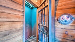 A wooden hallway with a blue door and a round window with a metal frame. - Davenport Retreat w/ Themed Rooms, Patio & Pool! (Davenport)