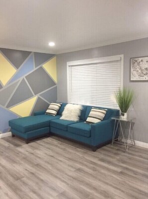Relax in this stylish living room with a comfortable sofa, geometric-patterned wall, and natural light pouring in through the window.