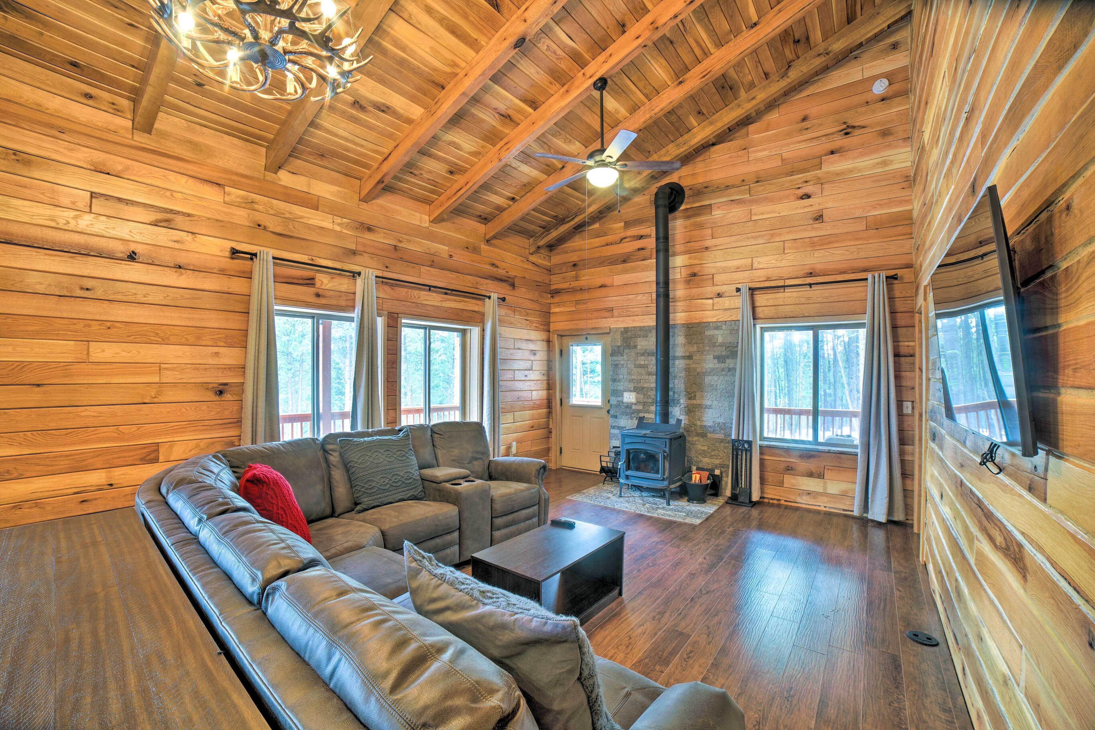 A log cabin interior with a large sofa, fireplace, and wooden walls.