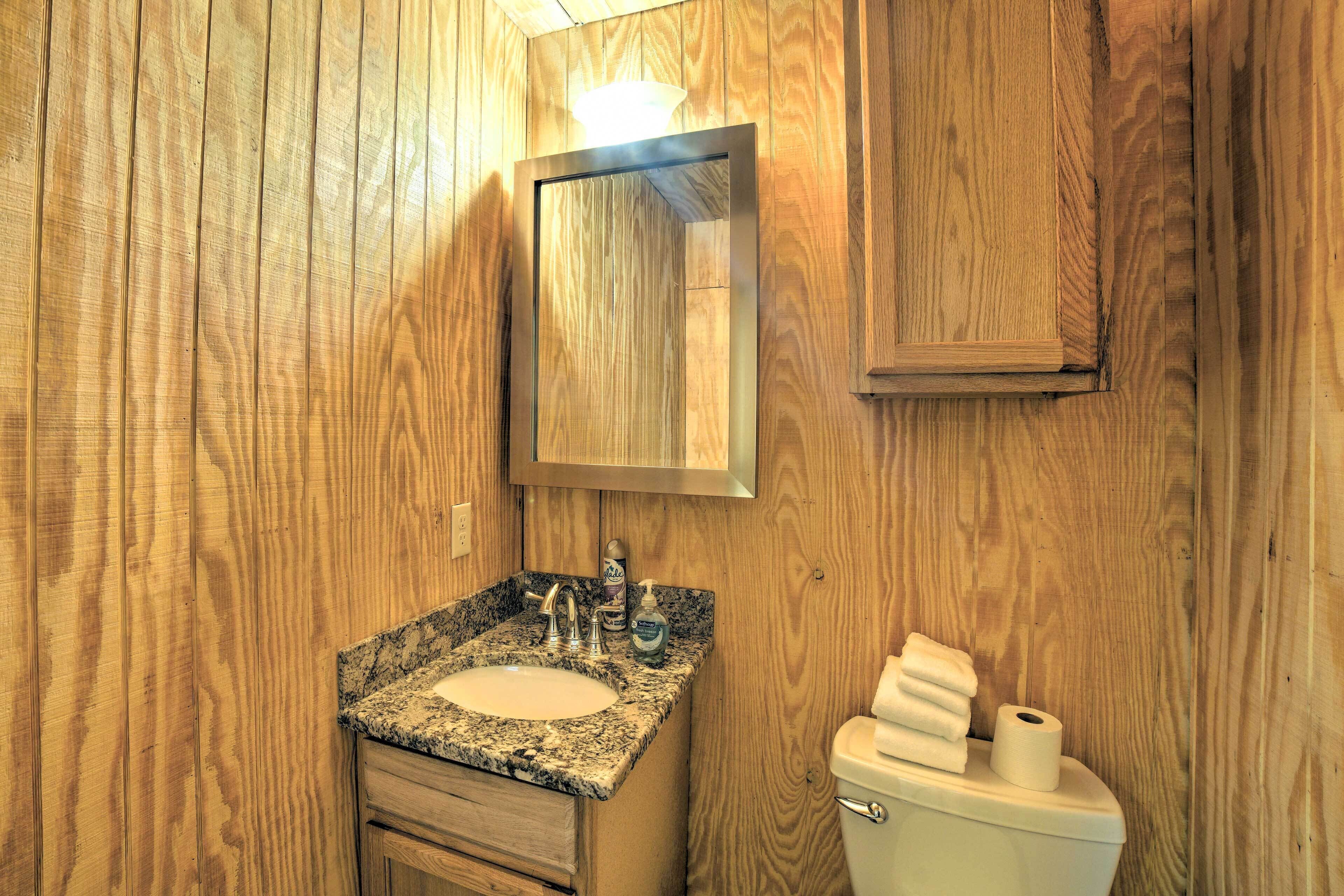 A wooden-paneled bathroom with a granite sink, a mirror, and a toilet.