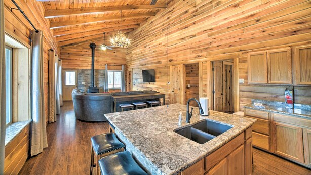 A spacious kitchen with a granite countertop, wooden cabinets, and a large island with seating. - Woodsy Mountain Cabin: 2 Mi to Angel Fire Resort! (Angel Fire)