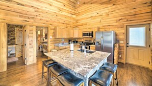 A spacious kitchen with wooden walls, a granite island, and modern appliances. - Woodsy Mountain Cabin: 2 Mi to Angel Fire Resort! (Angel Fire)