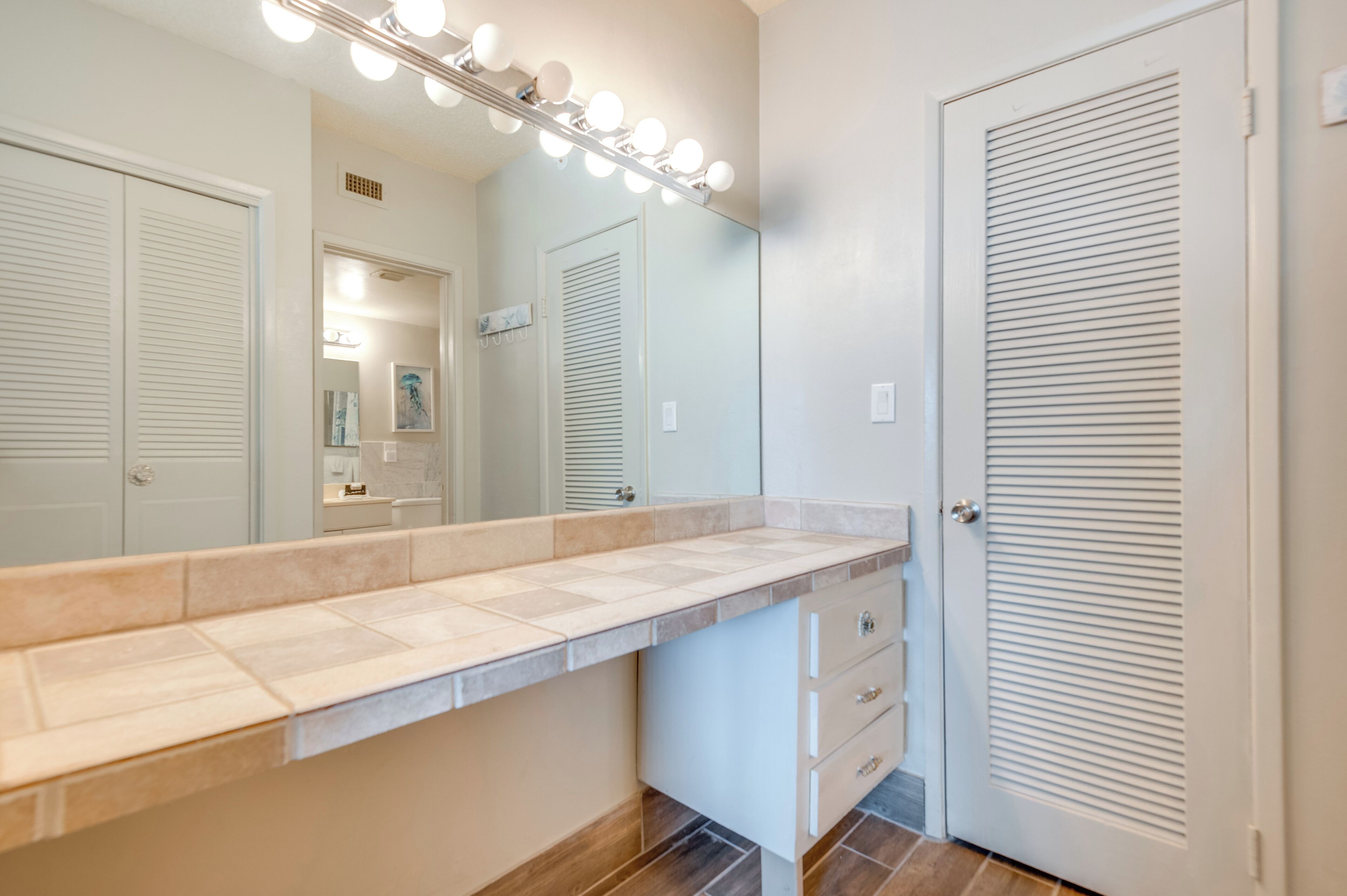 A bathroom with a vanity, mirror, and lights.