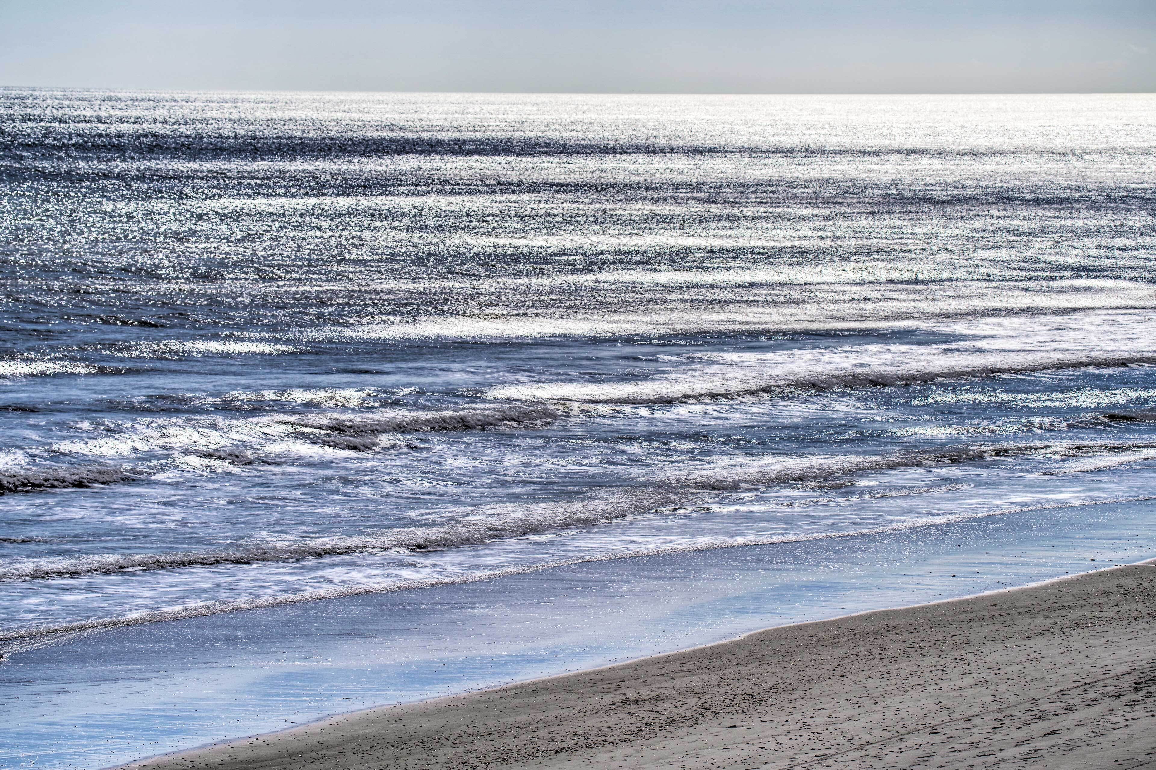A beach with waves and a clear sky.