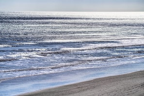 A beach with waves and a clear sky.