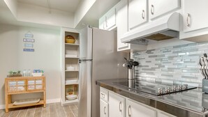 A modern kitchen with white cabinetry, a stainless steel refrigerator, a black countertop, and a tiled backsplash. - Direct Beach Access & View: Satellite Beach Condo! (Satellite Beach)