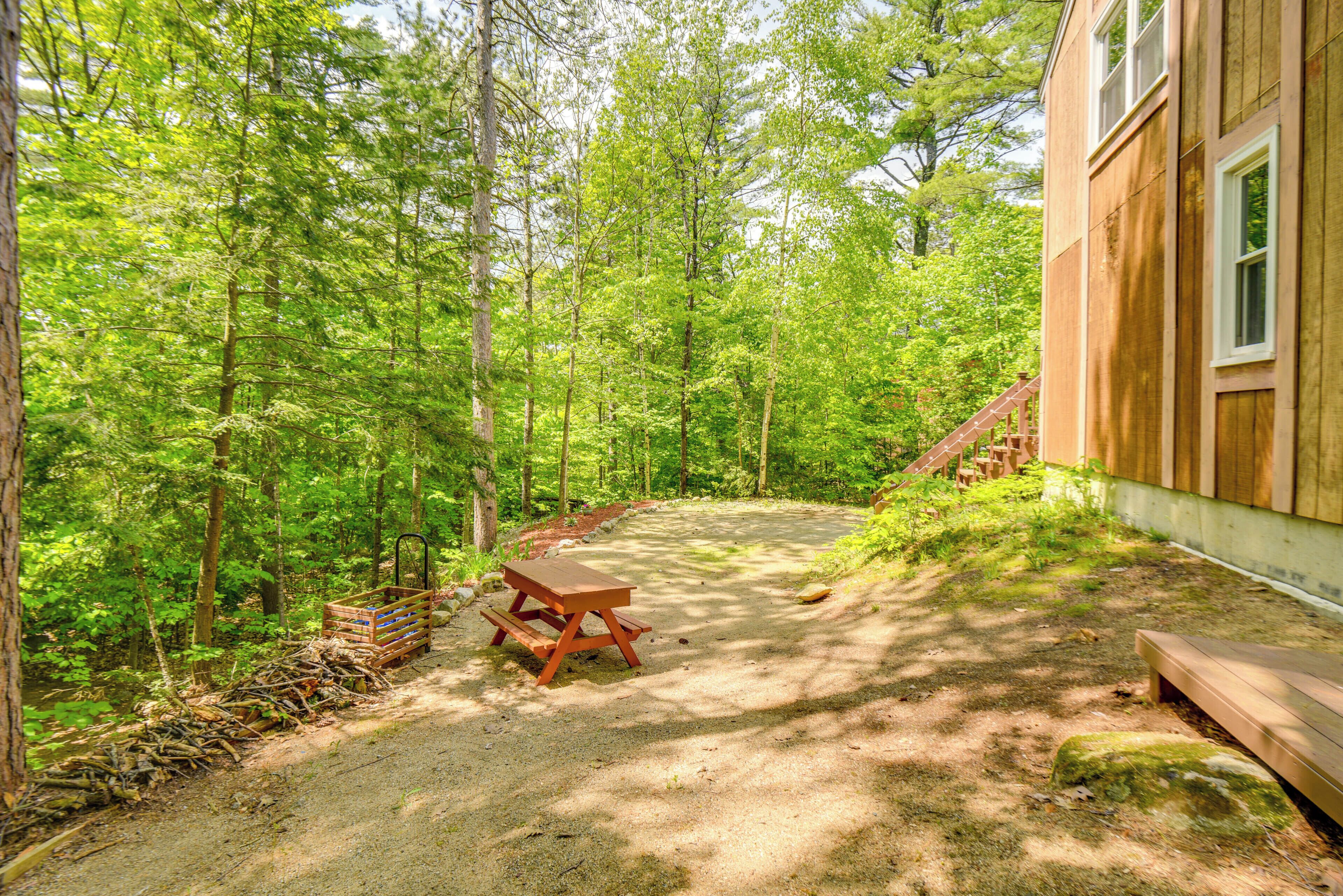 A picnic table in a forested area with a wooden building in the background.