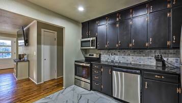 A modern kitchen with dark cabinets, stainless steel appliances, and a tiled backsplash.