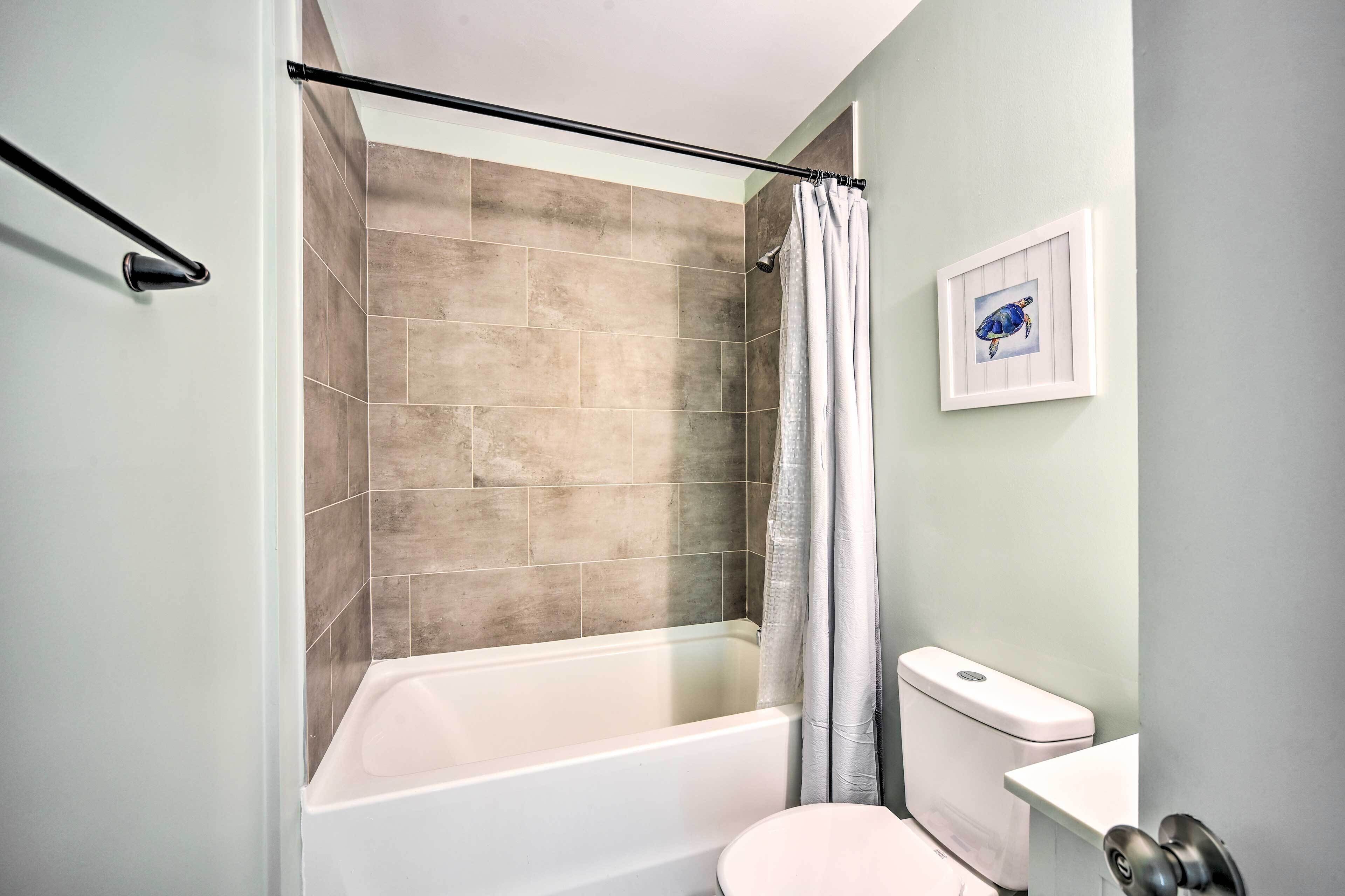 Ein Badezimmer mit Badewanne, Toilette und einem gerahmten Bild an der Wand.