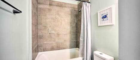 Ein Badezimmer mit Badewanne, Toilette und einem gerahmten Bild an der Wand.