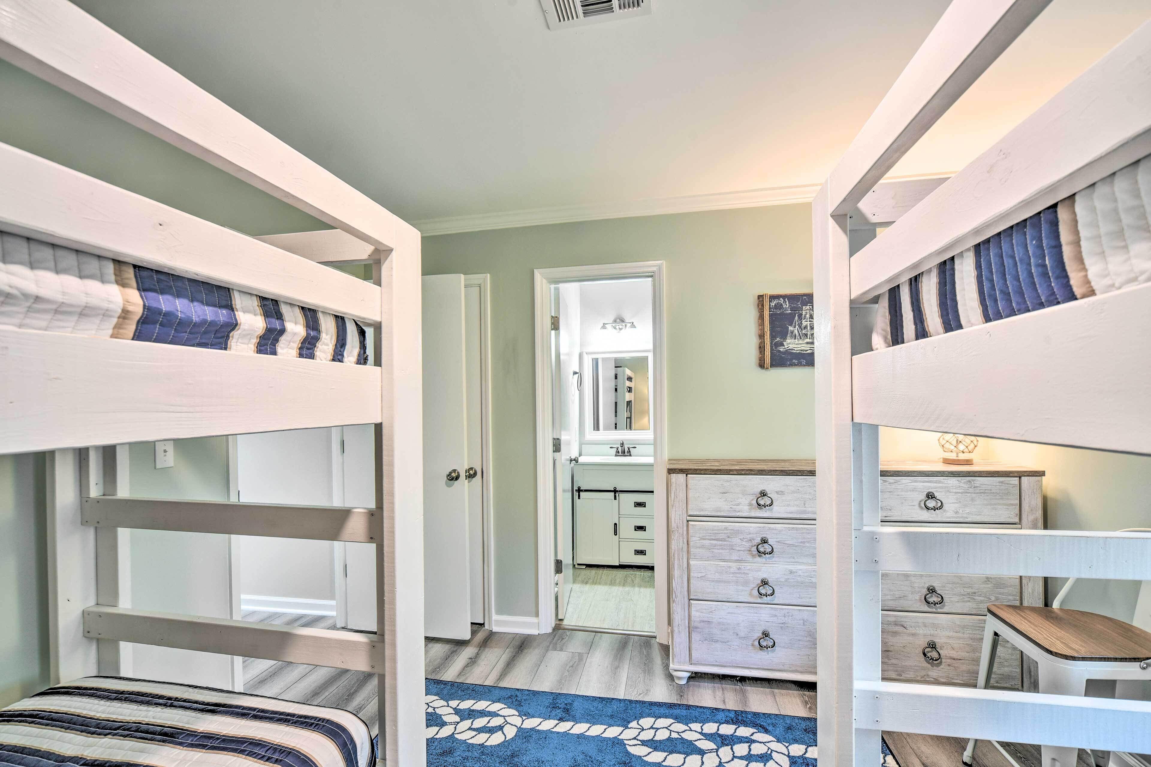 A bunk bed room with a dresser and a mirror.