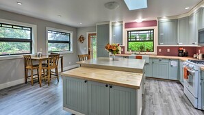 Una cocina moderna con una isla central, sillas de madera y una mesa de comedor.