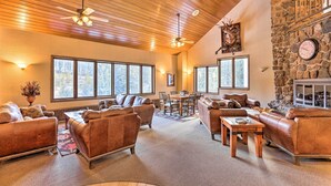 A spacious living room with leather sofas, a wooden ceiling, large windows, and a stone wall. - Cozy Ski-in/out Winter Park Studio w/ Hot Tubs! (Winter Park)