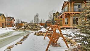 A residential area with houses, a wooden swing set, and a snow-covered landscape. - Fish, Hike & Ski: Riverfront Granby Cabin! (Granby)