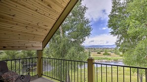A covered balcony with a view of a river and surrounding greenery. - Fish, Hike & Ski: Riverfront Granby Cabin! (Granby)