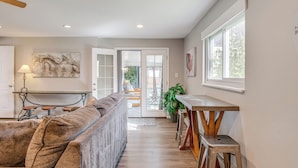 A modern living room with a sofa, a dining table, and a kitchen area with a window. - Dog-friendly Ranch Retreat ~ 5 Mi to Denver! (Edgewater)