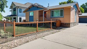 A two-story house with a front porch, a wooden fence, and a driveway.