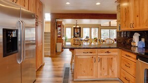 A kitchen with wooden cabinets, stainless steel appliances, and a central island with chairs. - Deck + Mtn View: Keystone Townhome Near Resort! (Keystone)