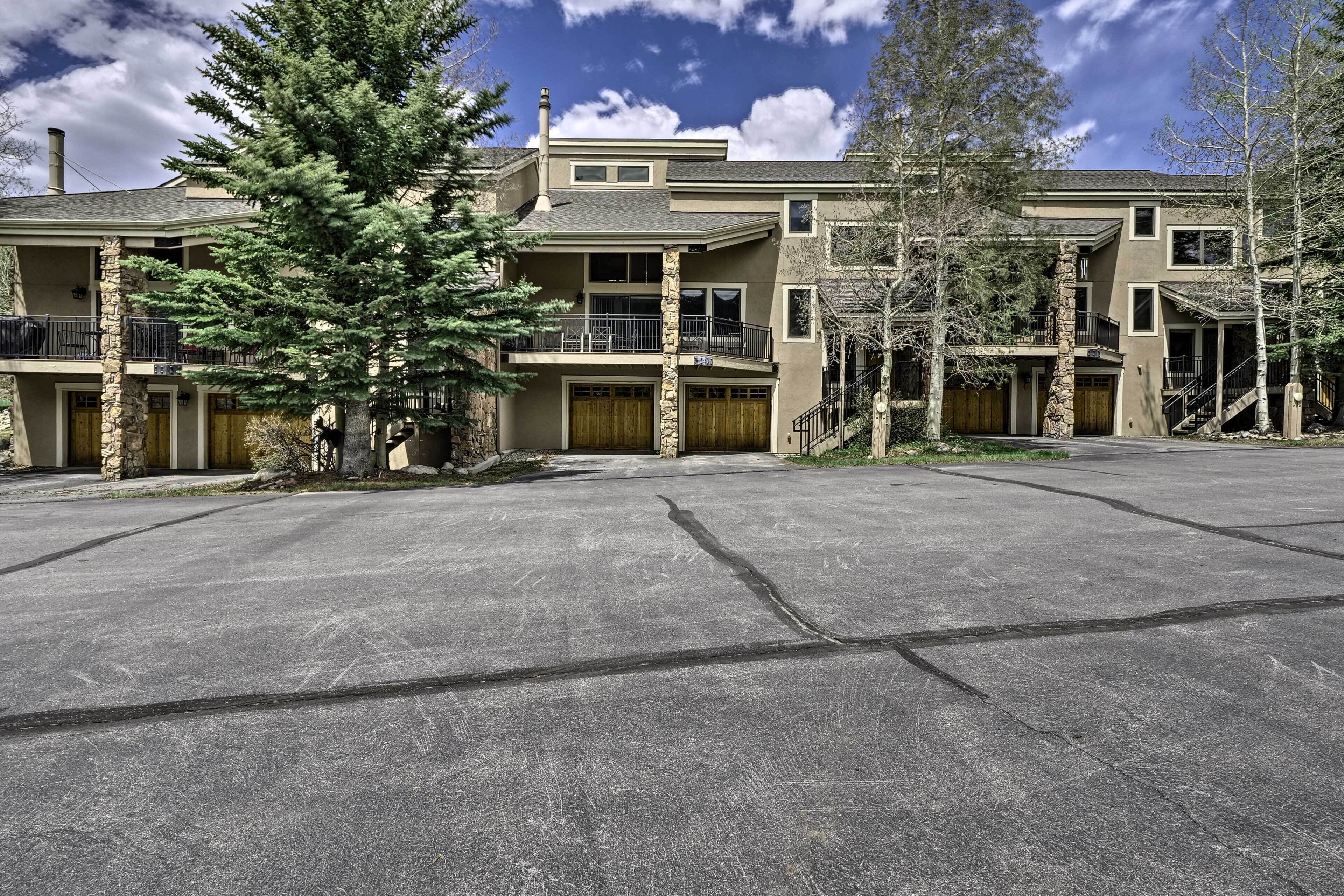 A multi-story building with a stone facade, multiple balconies, and a driveway.