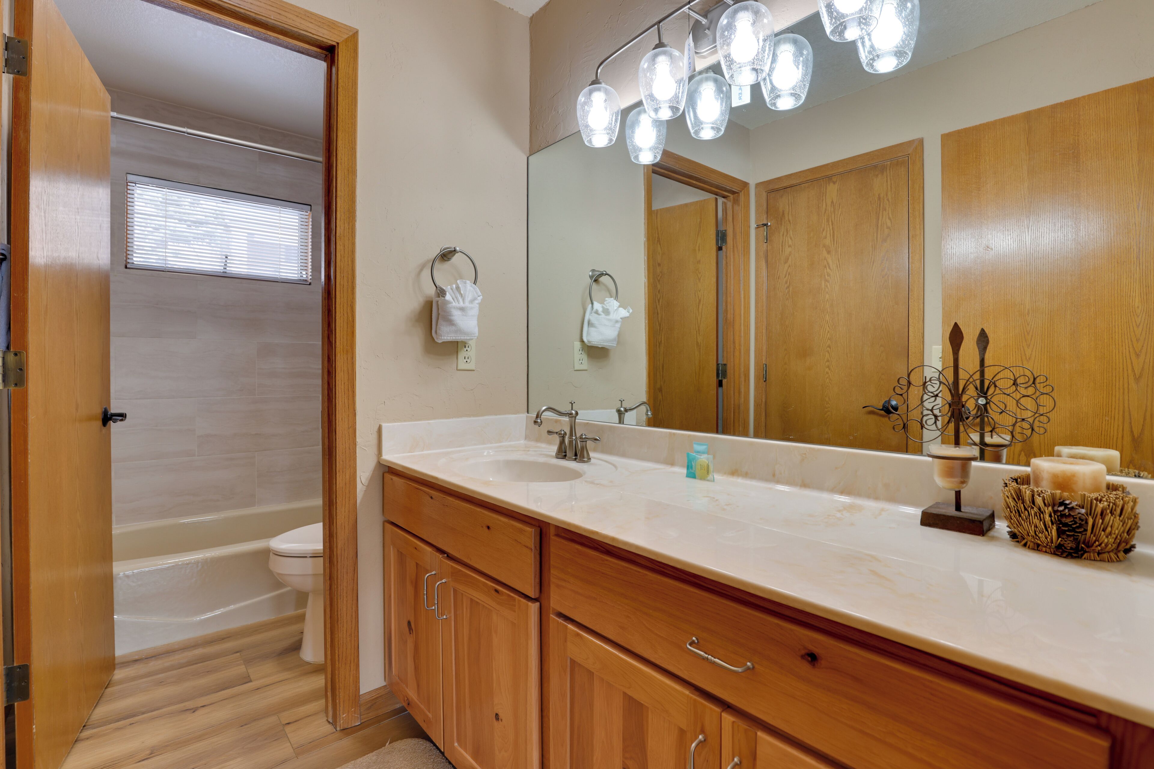 A bathroom with a wooden vanity, a large mirror, and a bathtub.