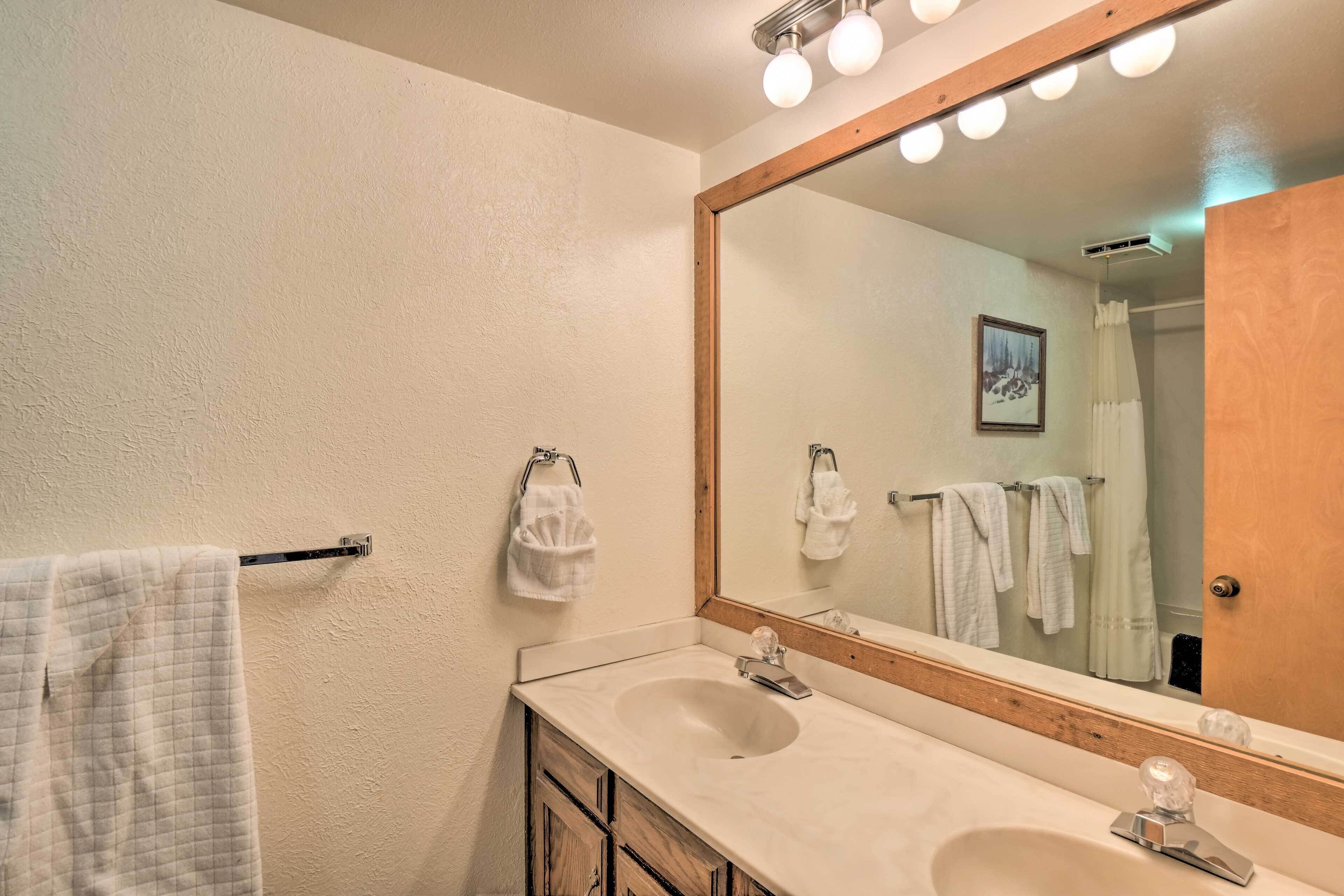 Une salle de bain avec deux lavabos, un grand miroir et un porte-serviettes.