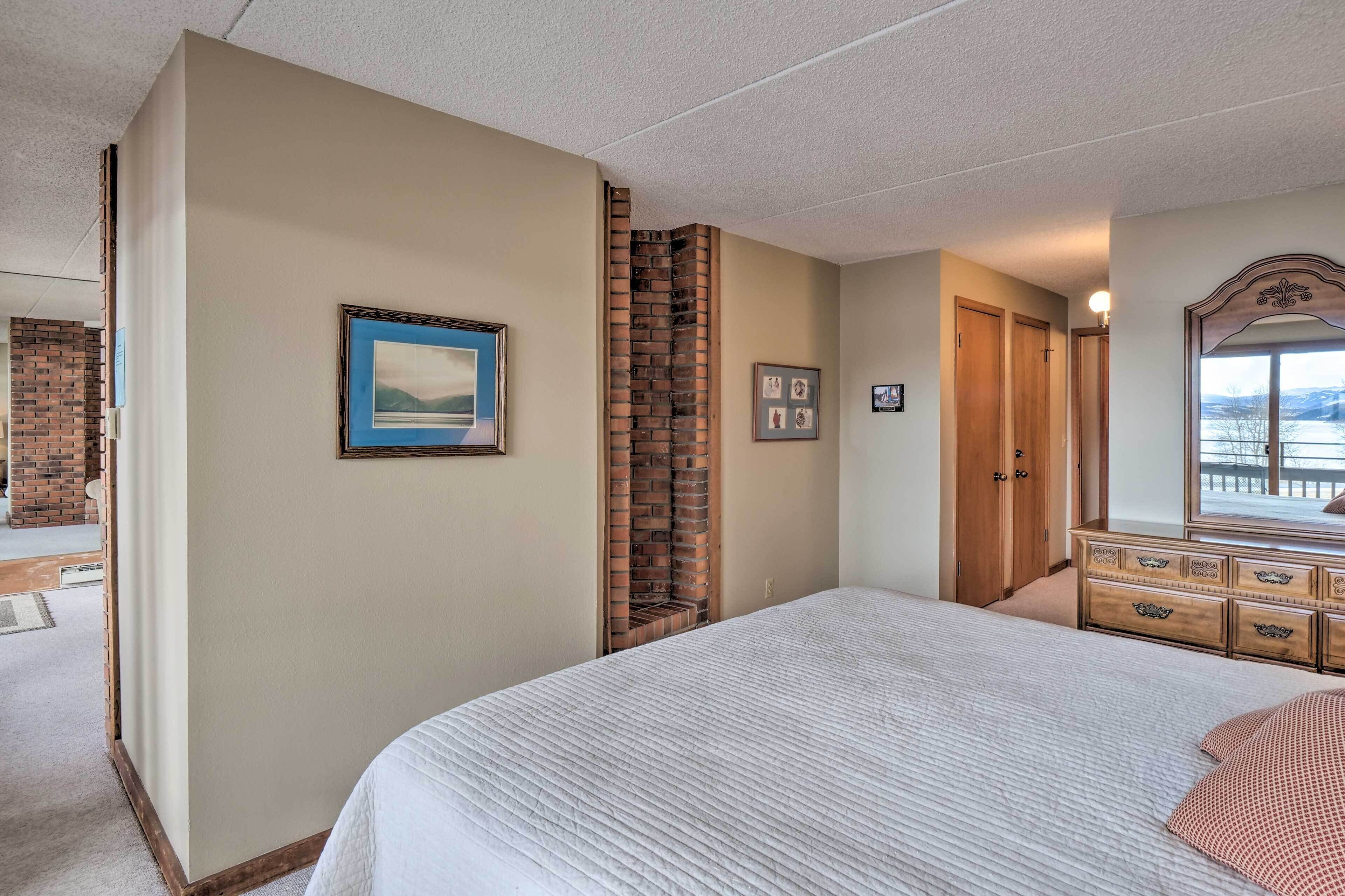 Quarto com uma cama grande, lareira de tijolos, guarda-roupa de madeira e vista para o exterior.