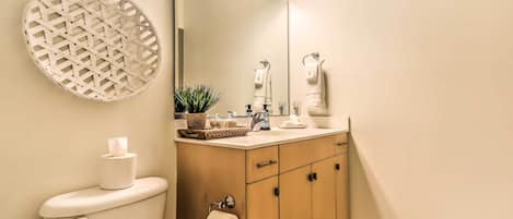 Een badkamer met toilet, wastafel, spiegel en handdoekhouder.