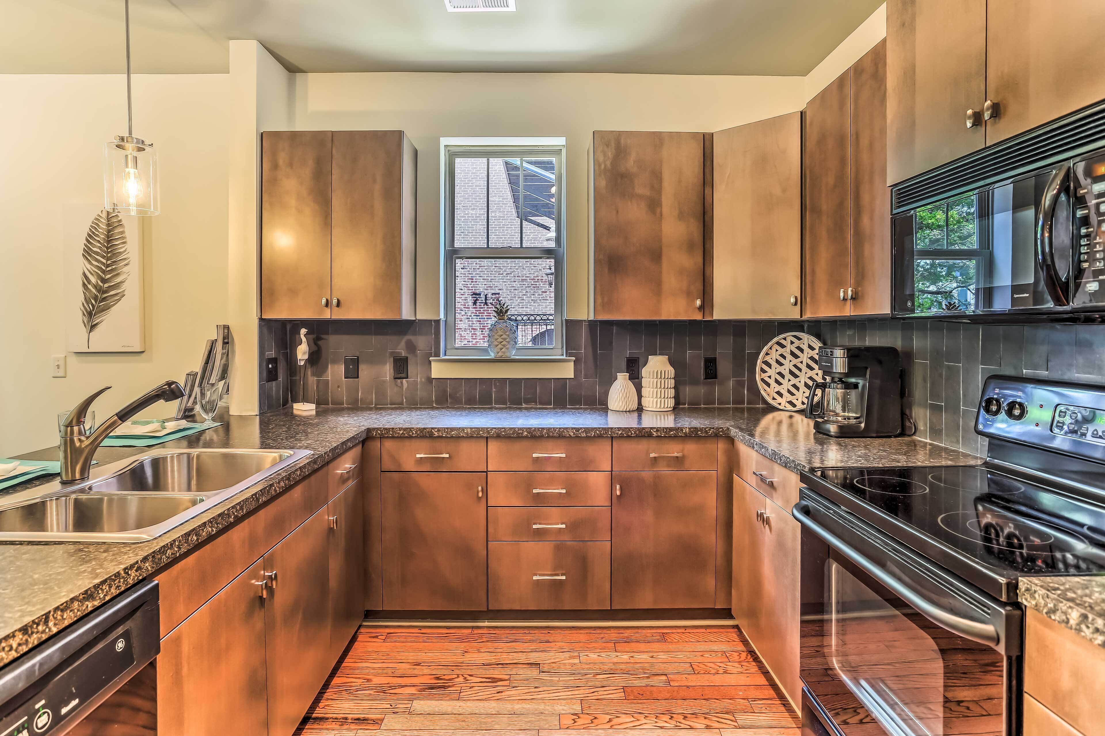 A modern kitchen with wooden cabinets, a stainless steel sink, a built-in oven, and a window with a view of the outside.
