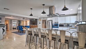 A modern kitchen with stainless steel appliances, a central island with bar stools, and pendant lighting. - Home w/ Private Pool - Near Las Vegas Strip! (Las Vegas)