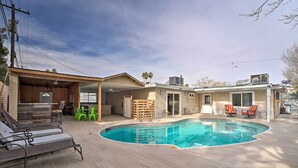 A backyard with a swimming pool, lounge chairs, and a covered patio area. - Home w/ Private Pool - Near Las Vegas Strip! (Las Vegas)