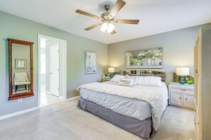 A bedroom with a bed, a ceiling fan, a nightstand, a lamp, and a painting on the wall. - Home Sweet Home' w/ Private Pool + Patio! (Knoxville)