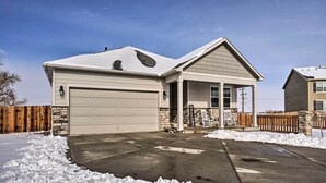 A single-story house with a garage, a covered porch, and a snow-covered driveway.