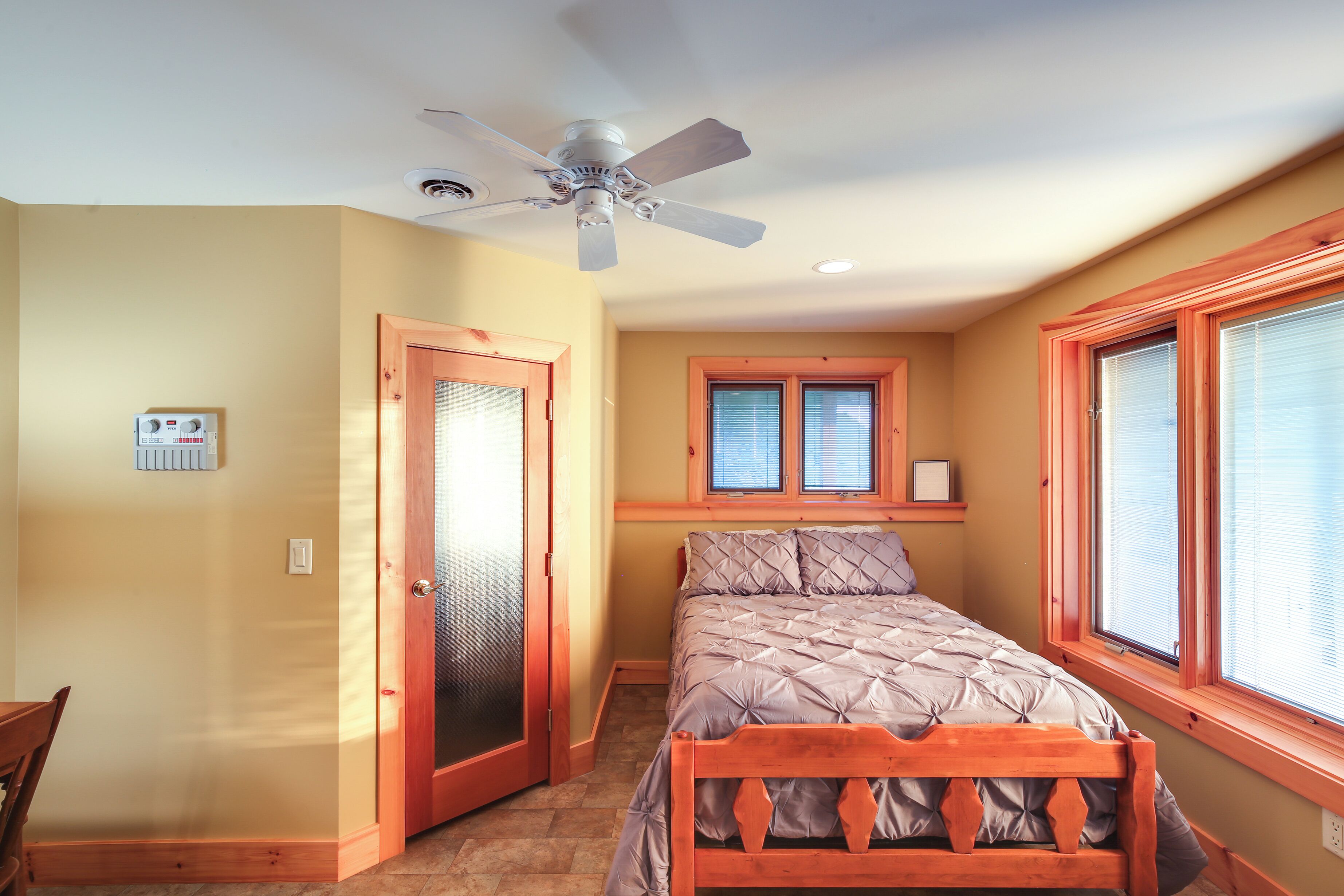 Ein Schlafzimmer mit Bett, Deckenventilator, Fenster und Tür.