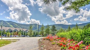A parking lot with a building in the background, surrounded by greenery and mountains. - 2-story Townhouse - 1 Mi to Killington Ski Area! (Killington)