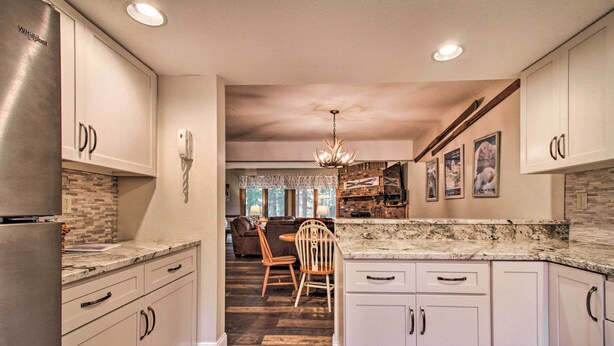 A kitchen with white cabinets, a marble countertop, and a dining area with a wooden table and chairs. - 2-story Townhouse - 1 Mi to Killington Ski Area! (Killington)