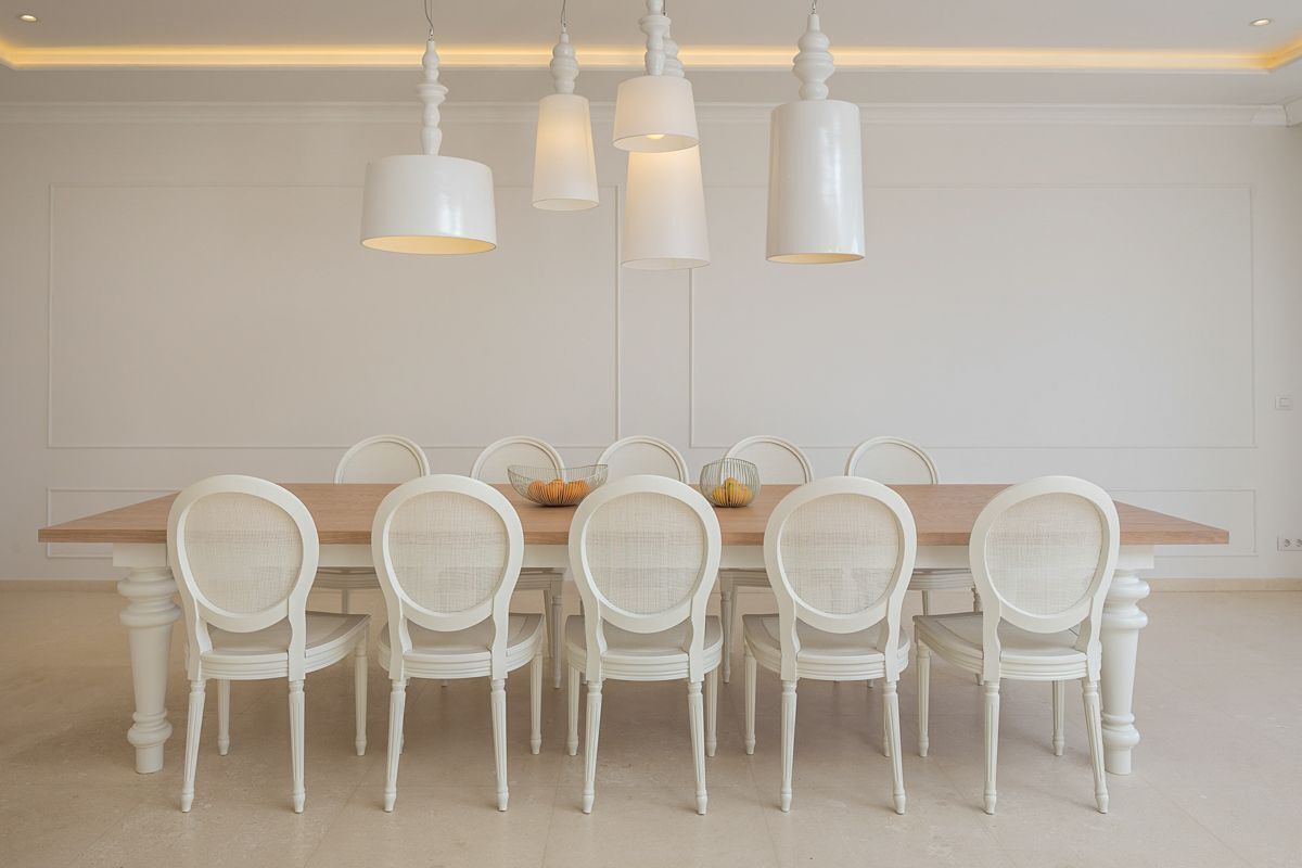Un comedor con una mesa de madera y seis sillas blancas.