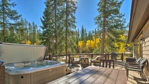 A wooden deck with a hot tub, outdoor furniture, and a view of a forest with autumn foliage. - Luxury 4 BR Cabin: 2 King Suites on Shuttle Route (Winter Park)