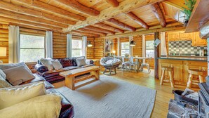A log cabin interior with a living room, dining area, and kitchen.