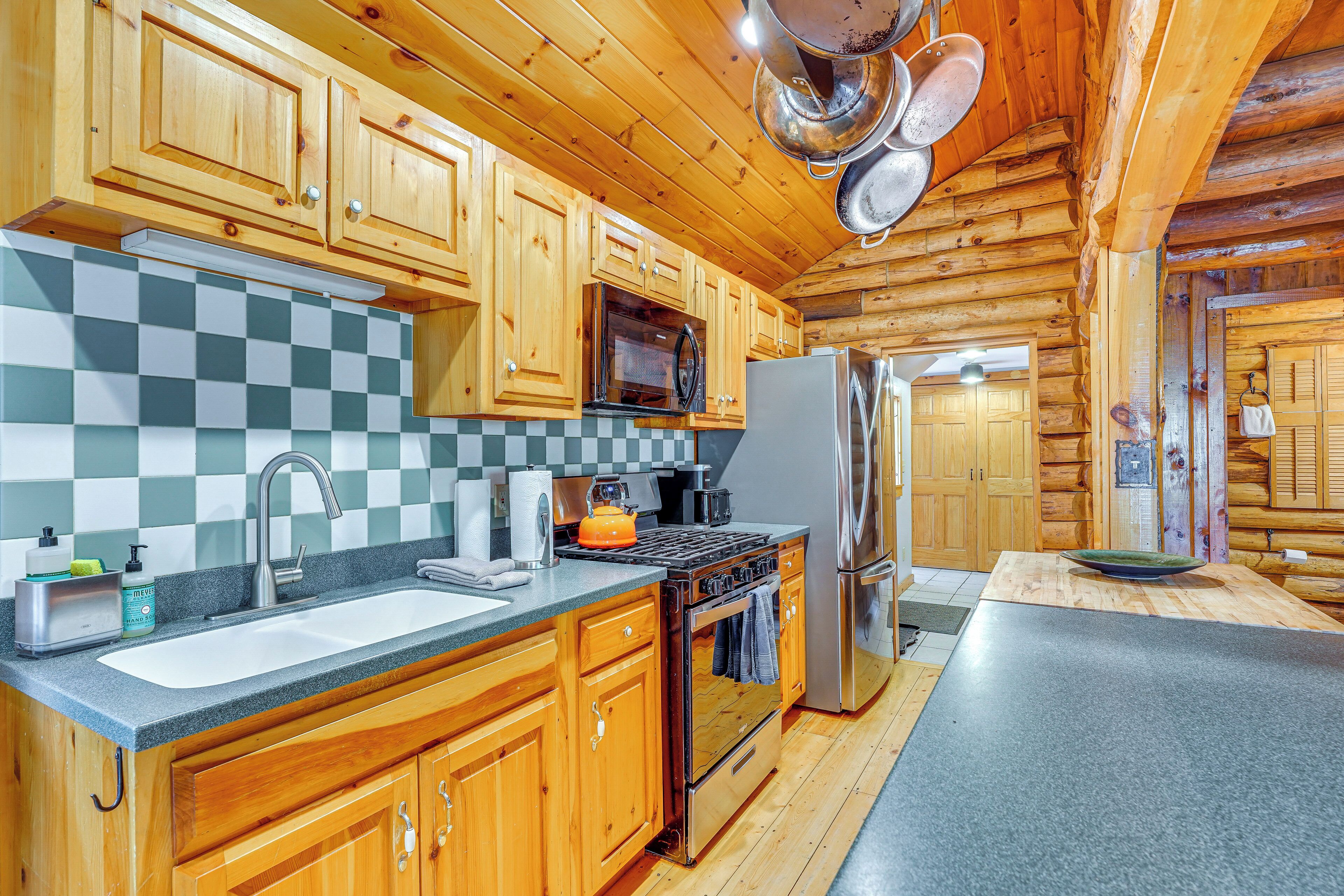 A kitchen with wooden cabinets, a stainless steel refrigerator, and a checkered backsplash.