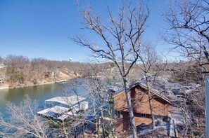 A cabin with a dock by a lake, surrounded by leafless trees and a clear sky. - Pool & Lake Access! 3rd-floor Osage Beach Retreat (Osage Beach)